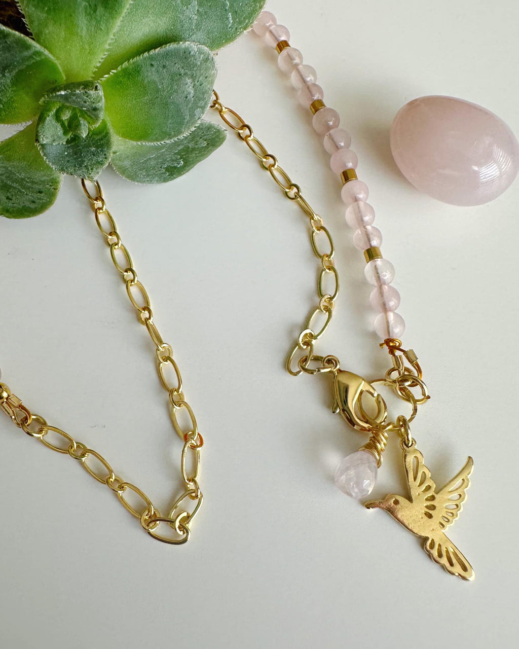 collar mitad cadena y mitad piedras pequeñas de  cuarzo rosa. lleva un colgante de colibri con gota de piedra cuarzo rosa.