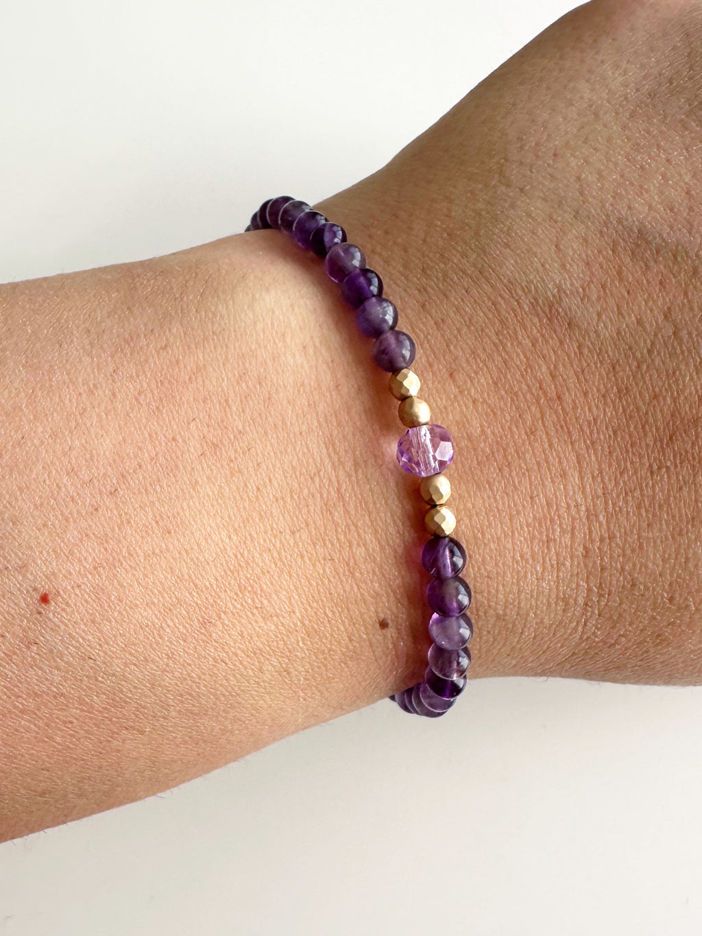 Se muestra la mano de la modelo utilizando la pulsera de piedras amatistas para el signo de leo