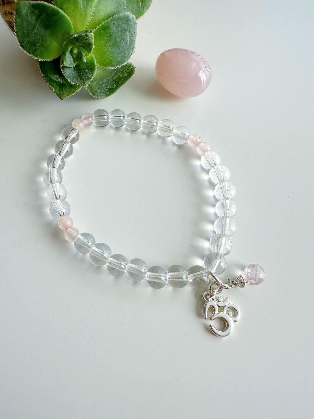 pulsera de mujer con simbolo om en piedras de cuarzo: cuarzo rosa y cuarzo cristal